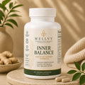 Supplement bottle labeled 'Wellyy Inner Balance' on a wooden surface with plants in the background